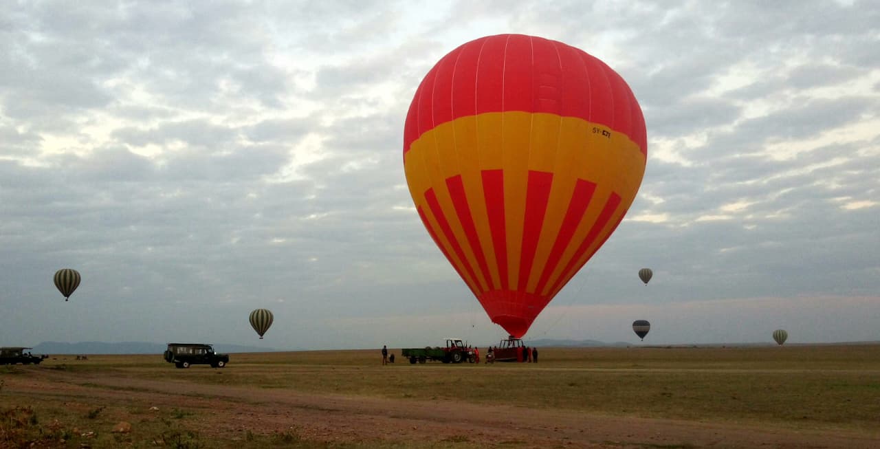 Couple enjoying a romantic hot air balloon ride over Kenya’s Maasai Mara during their honeymoon safari, with wildlife below