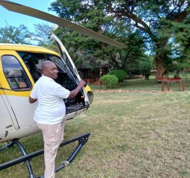 Client posing with a helicopter during the 4-Day Chalbi Desert & Lake Turkana Luxury Helicopter off the beaten track safari done by African Affarble Expedition Limited